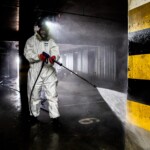 pracownik w ochronnej odzieży roboczej z lancą do czyszczenia hydrodynamicznego czyści ściany osmolone sadzą