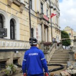 Pracownik operacyjny spółki Climbex w odzieży roboczej przed Urzędem Miasta w Lądku Zdroju po powodzi